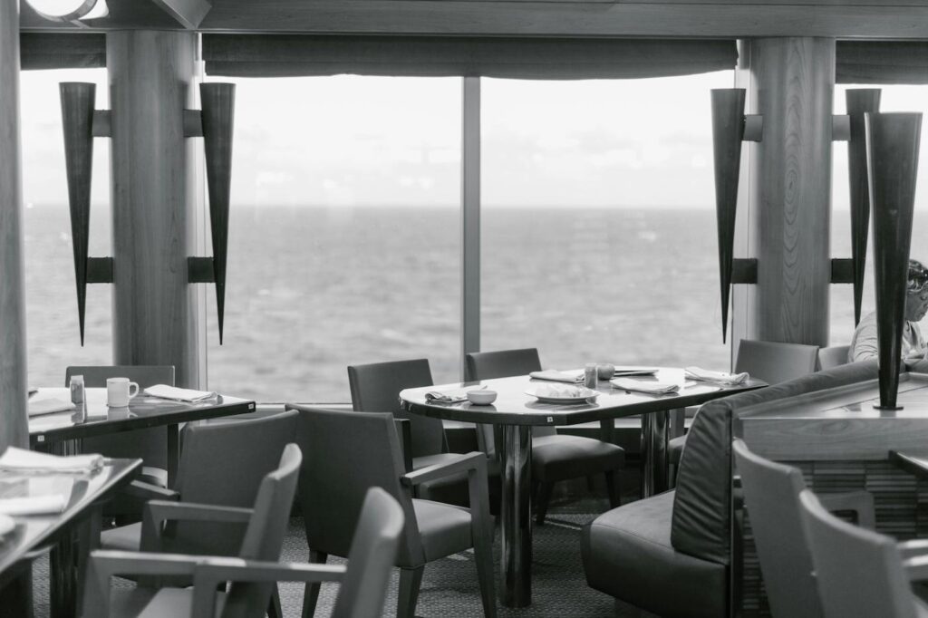 An empty restaurant full of set tables, with walls that are lined with windows.