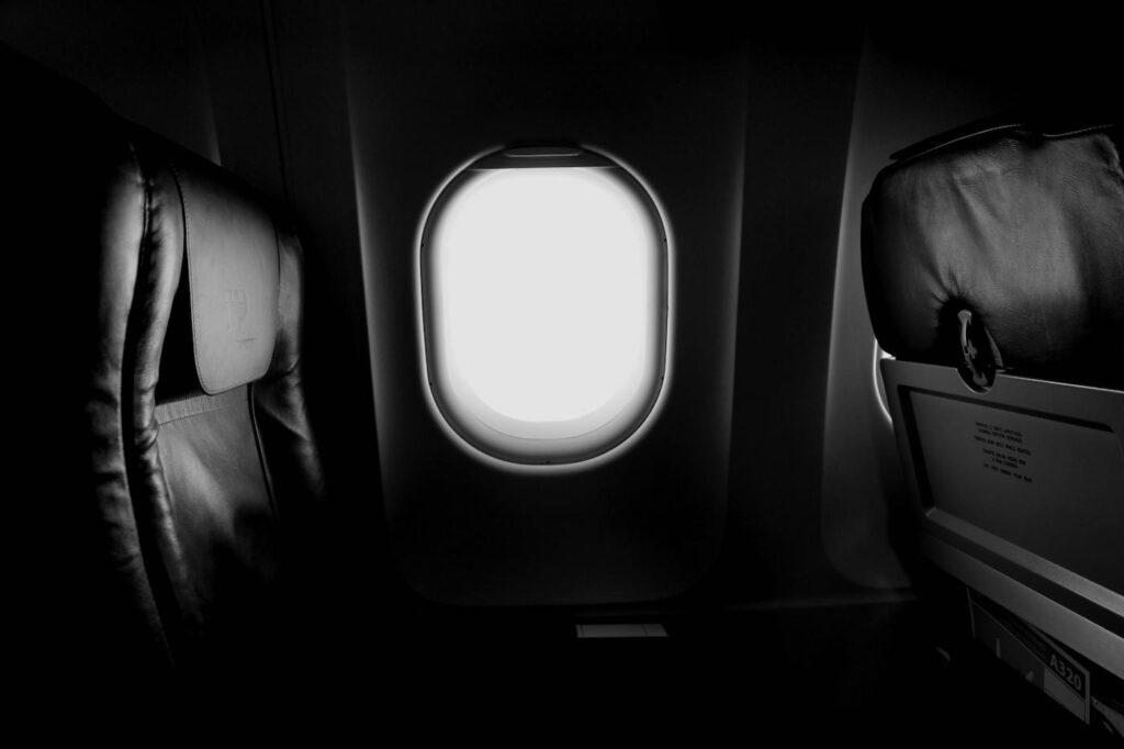 An empty seat on a plane with a view of clouds out the window.